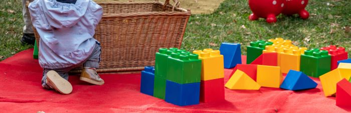 Kindesunterhalt: kleines Kind auf roter Decke spielt mit bunten Bausteinen